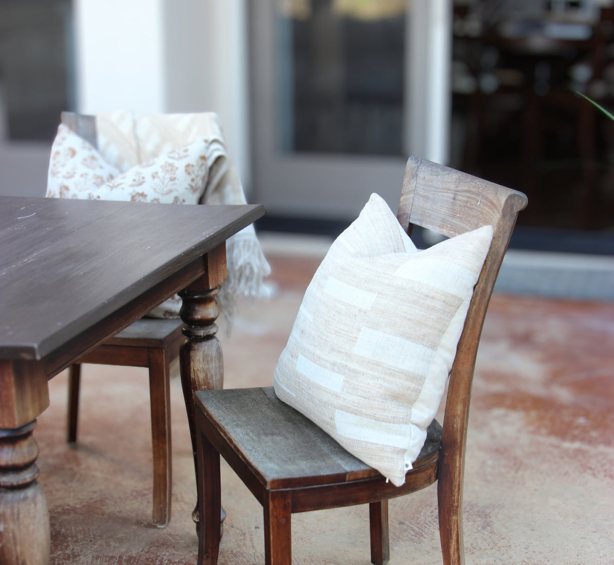 Diwan handwoven wool and silk cushion in Montecito: ivory blocks on taupe and sand, outdoors