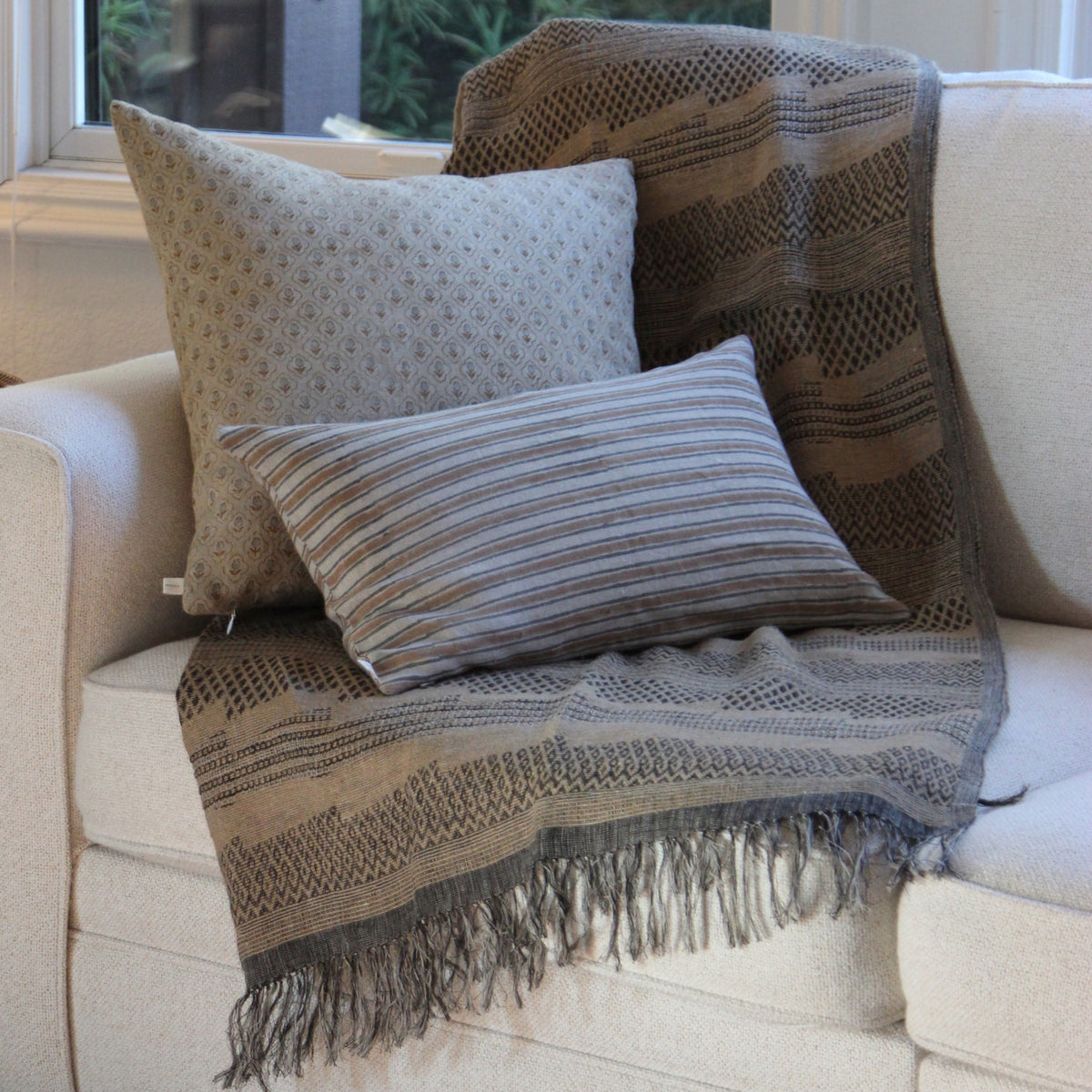 Diwan handwoven throw with fringe on a sofa with a hand block printed cushion cover and striped lumbar cover