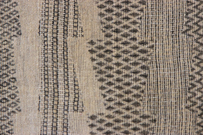 Close-up of the Diwan linen and silk throw in Half Moon Bay: charcoal geometric pattern on beige