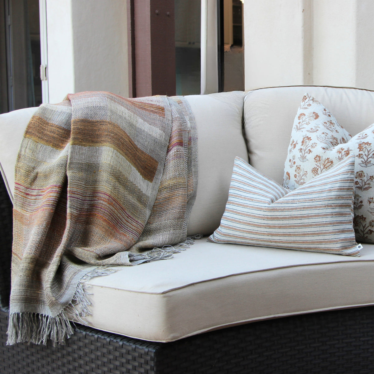 Diwan handwoven linen and silk throw in Ojai on a patio sofa with cushions