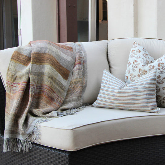 Diwan handwoven linen and silk throw in Ojai on a patio sofa with cushions